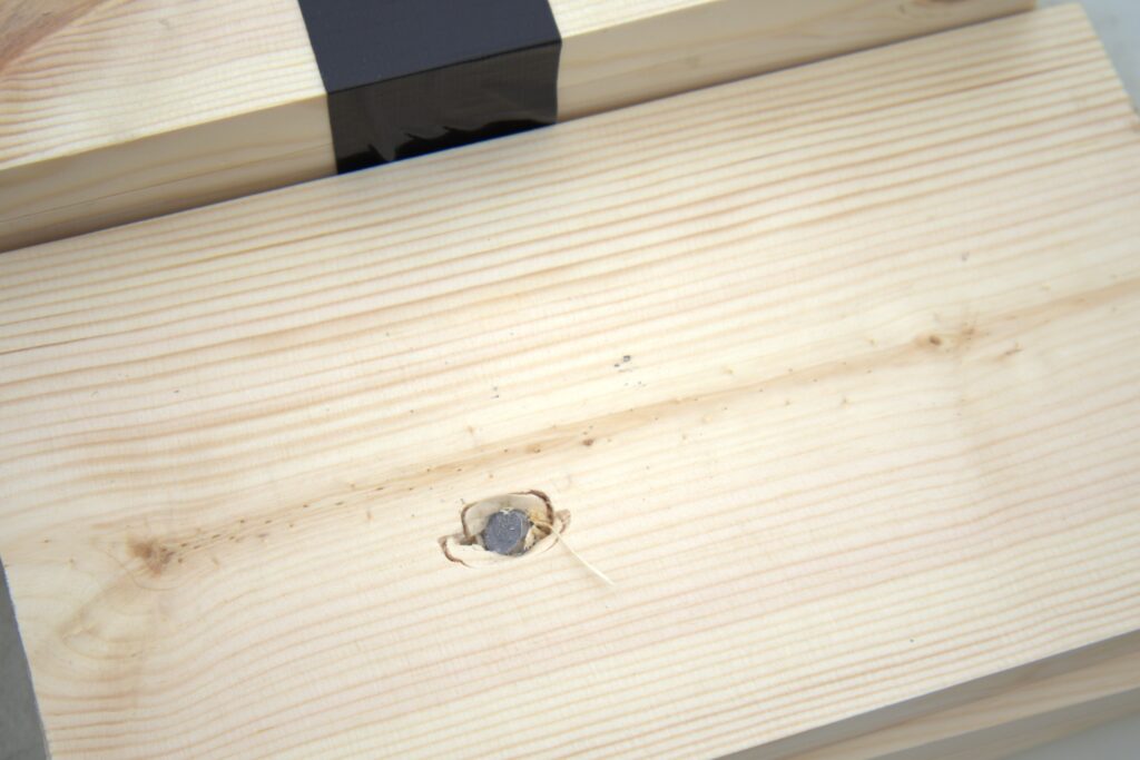 double tap 10mm hard cast retrieved bullet in a pine board